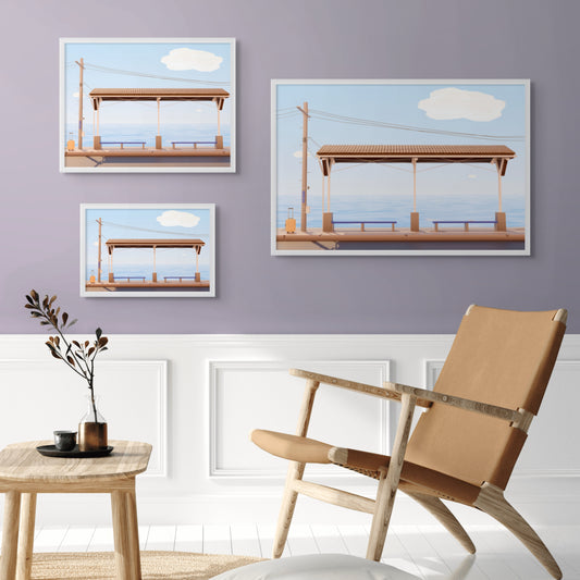 Three low poly style framed artworks of shimonada train station with sea on background displayed on a wall with a chair and side table in the foreground.