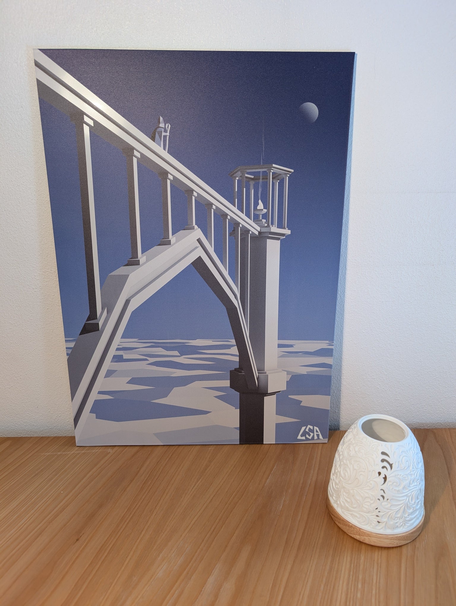 A surreal architectural aluminium print depicting a white arched bridge structure under a deep blue sky with a small moon, shown against a light textured background.
