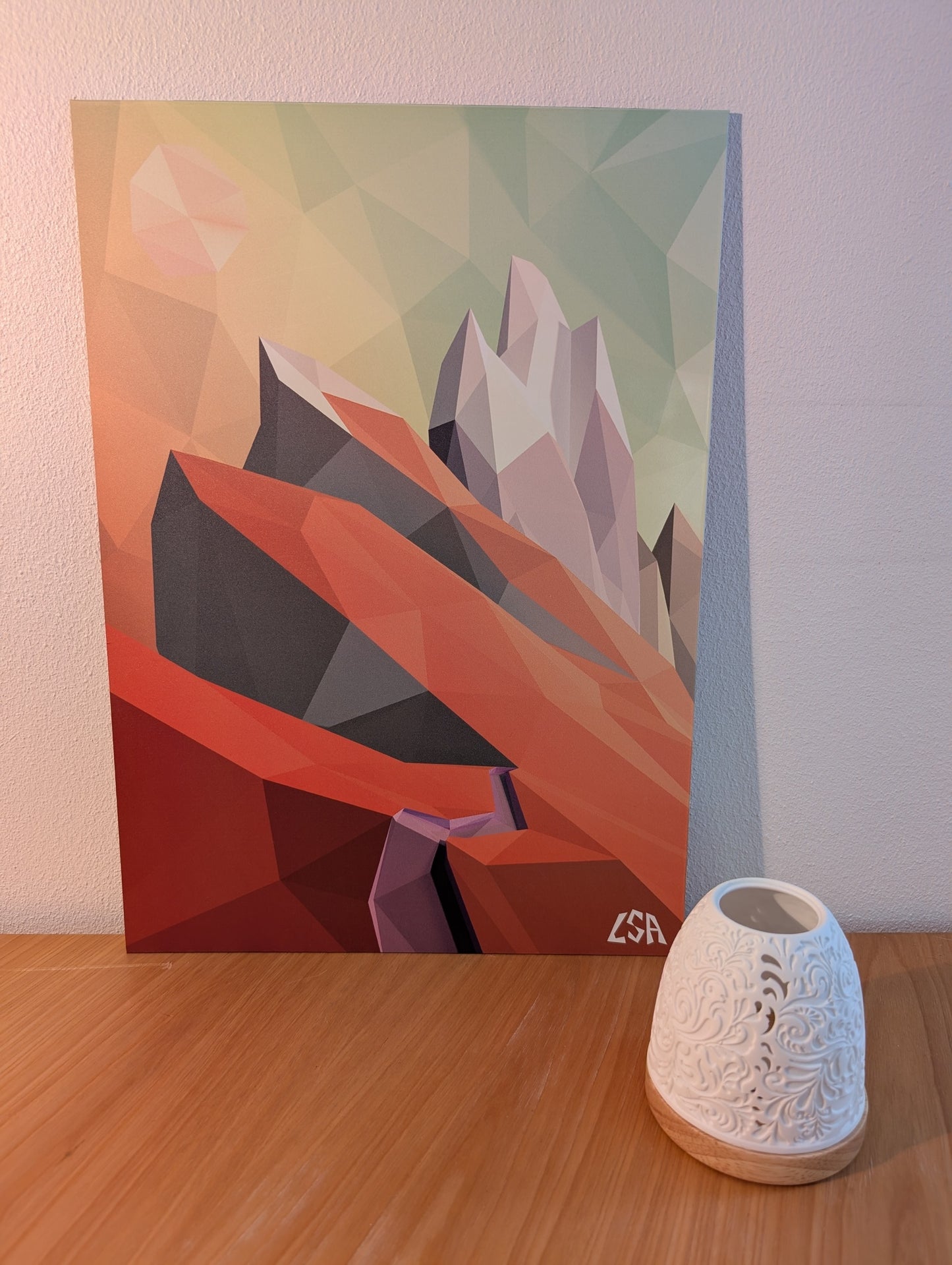 A low-poly geometric aluminium print featuring abstract mountains in orange, red, gray